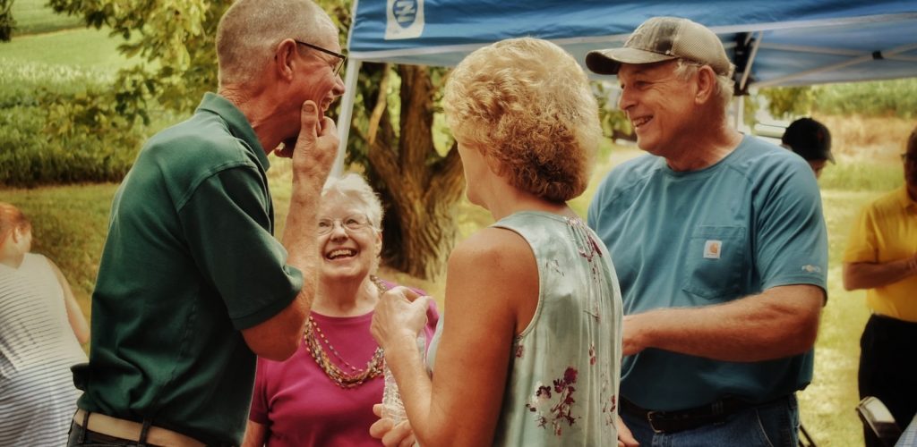 man in green polo shirt holding woman in white floral sleeveless dress